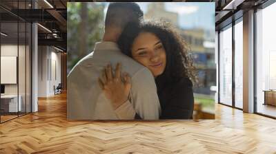 Affectionate woman embracing man in a sunny urban park, showcasing love and tenderness. Wall mural