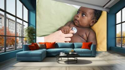 African american baby having medical examination sitting on bed at bedroom Wall mural