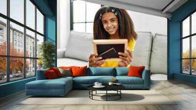 African american girl smiling confident looking picture at home Wall mural