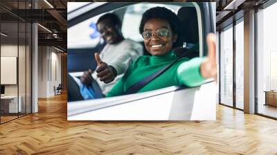 African american man and woman couple doing ok gesture sitting on car at street Wall mural