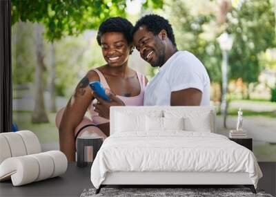 African american man and woman couple holding yoga mat using smartphone at park Wall mural