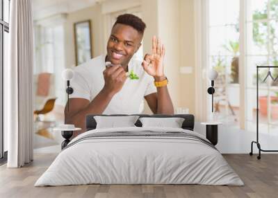 African american man eating fresh healthy salad doing ok sign with fingers, excellent symbol Wall mural