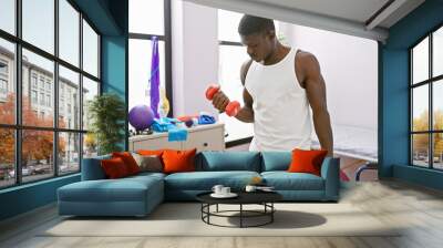 African american man exercising with dumbbells in a physical therapy clinic Wall mural