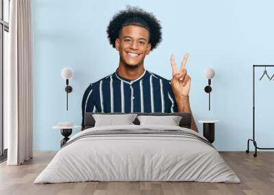 African american man with afro hair wearing casual clothes showing and pointing up with fingers number two while smiling confident and happy. Wall mural