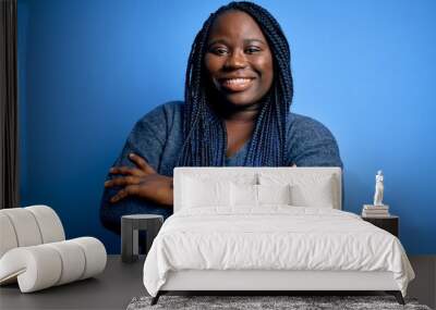 African american plus size woman with braids wearing casual sweater over blue background happy face smiling with crossed arms looking at the camera. Positive person. Wall mural