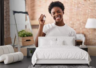 African american woman holding keys of new home looking positive and happy standing and smiling with a confident smile showing teeth Wall mural