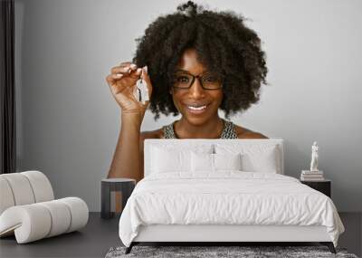 African american woman real state agent holding keys of new home smiling over isolated white background Wall mural