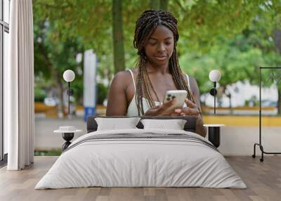 African american woman using smartphone with serious expression at park Wall mural