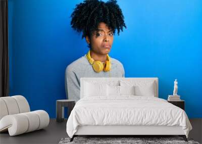 African american woman with afro hair using smartphone typing message skeptic and nervous, frowning upset because of problem. negative person. Wall mural