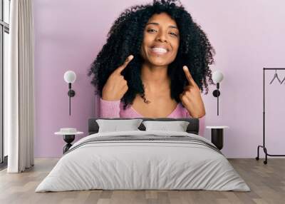 African american woman with afro hair wearing casual pink shirt smiling cheerful showing and pointing with fingers teeth and mouth. dental health concept. Wall mural