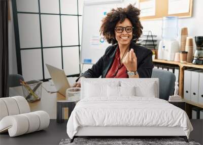 African american woman with afro hair working at the office wearing operator headset beckoning come here gesture with hand inviting welcoming happy and smiling Wall mural