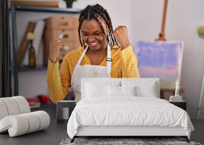 African american woman with braids at art studio very happy and excited doing winner gesture with arms raised, smiling and screaming for success. celebration concept. Wall mural