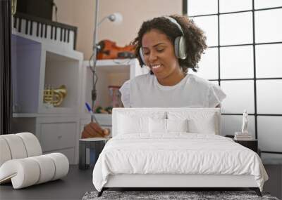 African american woman with headphones writing in music studio Wall mural