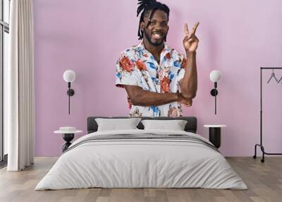 African man with dreadlocks wearing summer shirt over pink background smiling with happy face winking at the camera doing victory sign. number two. Wall mural