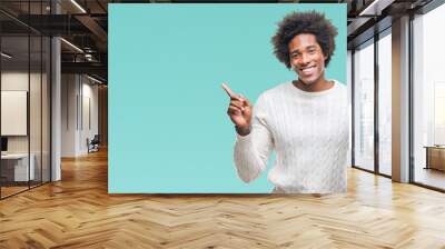 Afro american man holding vintage alarm clock over isolated background very happy pointing with hand and finger to the side Wall mural