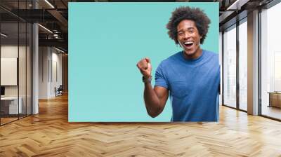 Afro american man over isolated background celebrating surprised and amazed for success with arms raised and open eyes. Winner concept. Wall mural