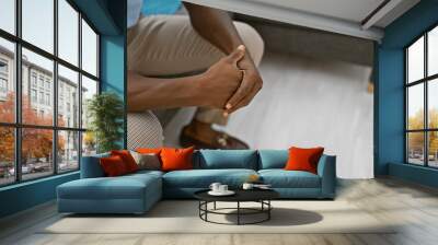 An african american man sitting thoughtfully in a modern living room, wearing casual attire. Wall mural