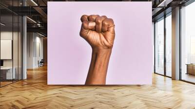 Arm and hand of black middle age woman over pink isolated background doing protest and revolution gesture, fist expressing force and power Wall mural