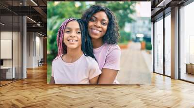 Beautiful african american mother and daughter smiling happy and hugging. Standing with smile on face standing at the park. Wall mural