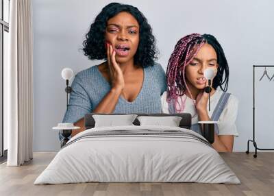 Beautiful african american mother and daughter wearing casual clothes and hugging touching mouth with hand with painful expression because of toothache or dental illness on teeth. dentist concept. Wall mural