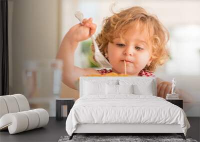 Beautiful blond child eating spaghetti with fork at home Wall mural