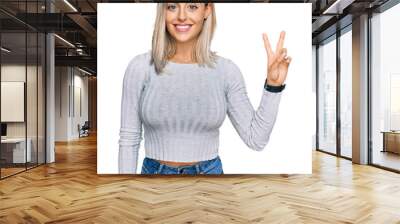 Beautiful blonde woman wearing casual clothes showing and pointing up with fingers number two while smiling confident and happy. Wall mural