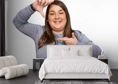 Beautiful brunette plus size woman wearing casual clothes smiling making frame with hands and fingers with happy face. creativity and photography concept. Wall mural