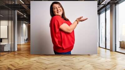 Beautiful brunette plus size woman wearing casual red t-shirt over isolated white background pointing aside with hands open palms showing copy space, presenting advertisement smiling excited happy Wall mural