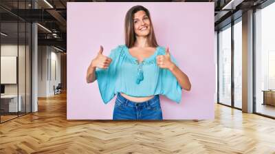 Beautiful caucasian woman wearing casual clothes success sign doing positive gesture with hand, thumbs up smiling and happy. cheerful expression and winner gesture. Wall mural