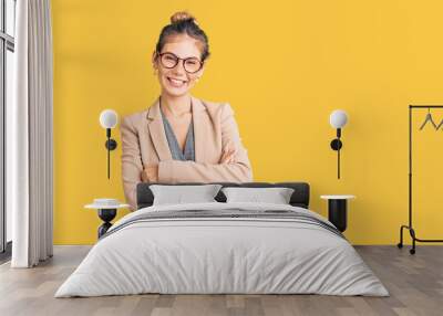 Beautiful caucasian woman with blonde hair wearing business jacket and glasses happy face smiling with crossed arms looking at the camera. positive person. Wall mural