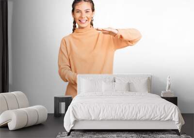 Beautiful caucasian woman with blonde hair wearing casual winter sweater gesturing with hands showing big and large size sign, measure symbol. smiling looking at the camera. measuring concept. Wall mural