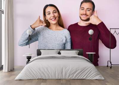 Beautiful couple wearing casual clothes smiling doing phone gesture with hand and fingers like talking on the telephone. communicating concepts. Wall mural