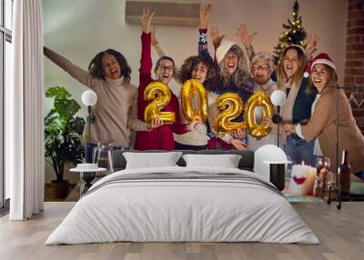 Beautiful group of women smiling happy and confident. Posing around christmas tree holding 2020 ballons at home Wall mural