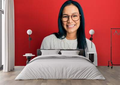 Beautiful hispanic woman wearing casual sweater and glasses looking positive and happy standing and smiling with a confident smile showing teeth Wall mural