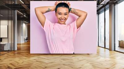 Beautiful hispanic woman with short hair wearing casual pink t shirt posing funny and crazy with fingers on head as bunny ears, smiling cheerful Wall mural