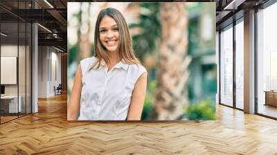 Beautiful latin teenager girl smiling happy standing at the park Wall mural