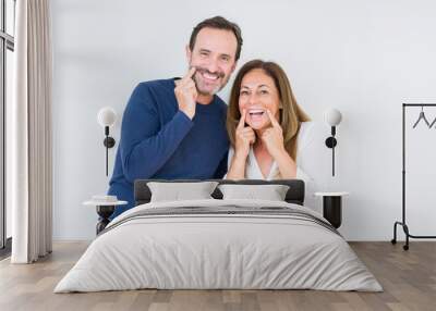 Beautiful middle age couple in love over isolated background Smiling with open mouth, fingers pointing and forcing cheerful smile Wall mural