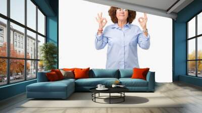 Beautiful middle ager senior businees woman wearing glasses over isolated background relax and smiling with eyes closed doing meditation gesture with fingers. Yoga concept. Wall mural