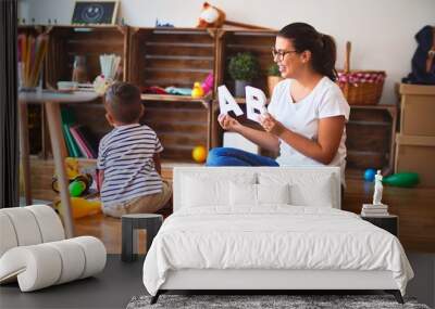 Beautiful teacher teaching alphabet to student toddler boy at kindergarten Wall mural