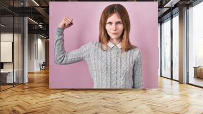 Beautiful woman standing over pink background strong person showing arm muscle, confident and proud of power Wall mural