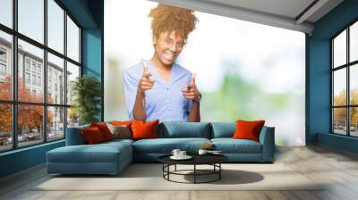 Beautiful young african american business woman over isolated background pointing fingers to camera with happy and funny face. Good energy and vibes. Wall mural