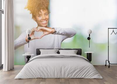 Beautiful young african american woman over isolated background smiling in love showing heart symbol and shape with hands. Romantic concept. Wall mural