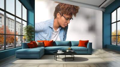 Beautiful young african american woman wearing glasses over isolated background Suffering of backache, touching back with hand, muscular pain Wall mural