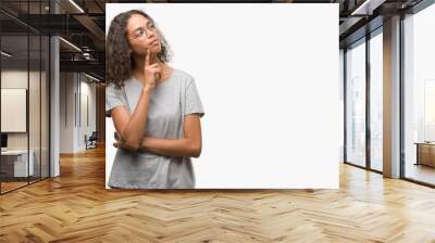 Beautiful young hispanic woman wearing glasses with hand on chin thinking about question, pensive expression. Smiling with thoughtful face. Doubt concept. Wall mural