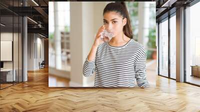 Beautiful young woman drinking a fresh glass of water at home Wall mural