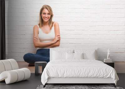 Beautiful young woman sitting on the floor at home happy face smiling with crossed arms looking at the camera. Positive person. Wall mural