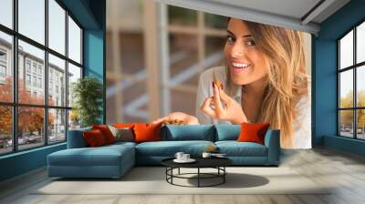 Beautiful young woman smiling and eating nuts at home. Healthy concept. Wall mural