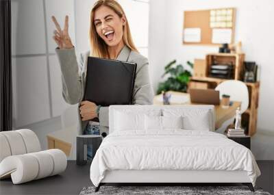 Blonde business woman at the office smiling with happy face winking at the camera doing victory sign with fingers. number two. Wall mural