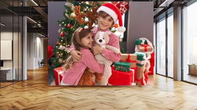 Brother and sister hugging each other standing by christmas gifts at home Wall mural