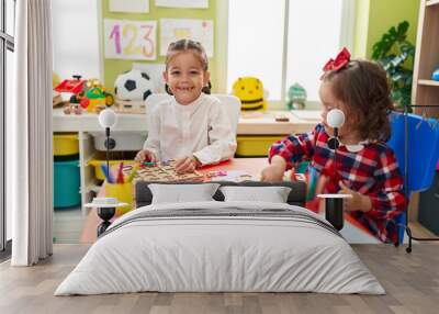 Brother and sister playing with maths puzzle game sitting on table at kindergarten Wall mural